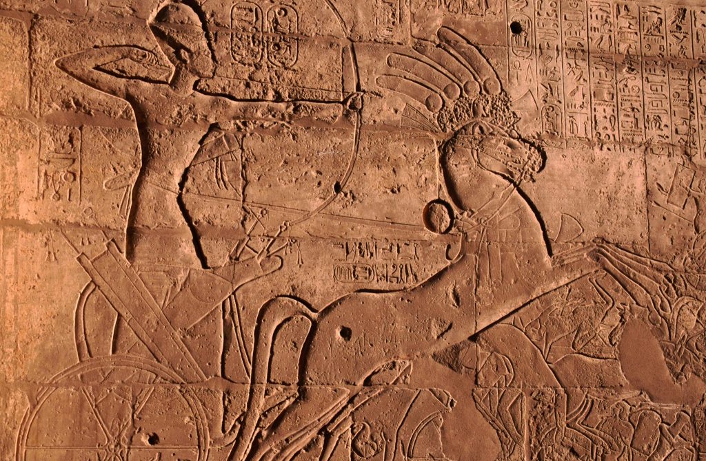 Ancient Egyptian relief of Ramesses II in a war chariot attacking enemies during the Battle of Kadesh, carved on temple walls in Abu Simbel.