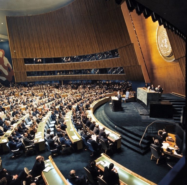 John F. Kennedy speaking at the lectern in the UN General Assembly